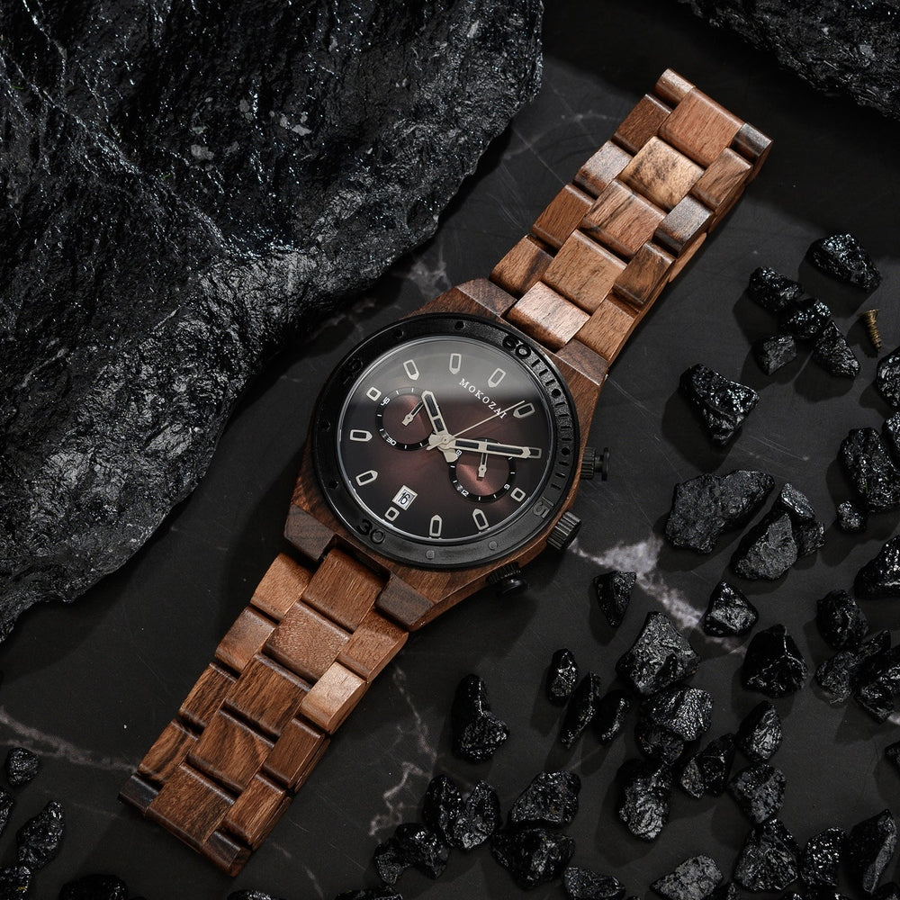 Mokozai wooden chronograph watch displayed on a dark marble surface, surrounded by black stones. The watch features a rich brown wooden band, black bezel, and sleek black dial with sub-dials, blending nature-inspired materials with contemporary style. Perfect for luxury and sustainable fashion in Australia.