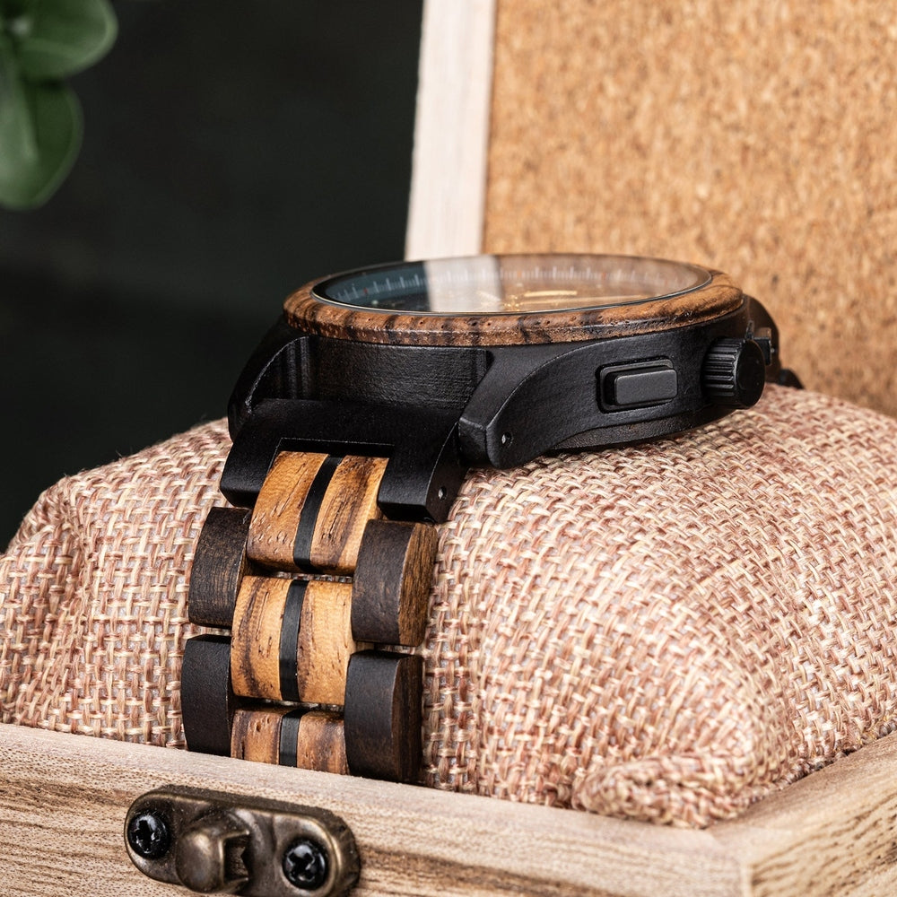 Close-up of a Mokozai wooden chronograph watch featuring a sleek black case, wood-accented strap, and detailed side view. Showcased on a burlap cushion, this design highlights natural wood grains combined with a bold black frame for an eco-conscious yet stylish timepiece.