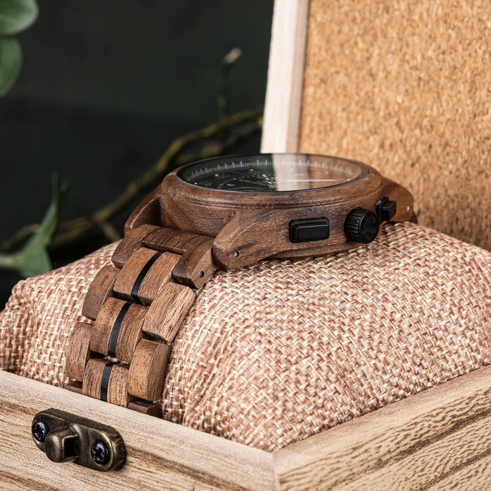Side view of a wooden wristwatch with a natural wood grain case and a matching wooden link bracelet, elegantly displayed on a textured cushion inside a rustic wooden box.