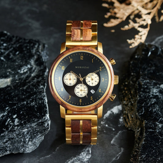 Elegant wooden and gold metal wristwatch with a black dial and chronograph, set against a dark stone background, showcasing its luxurious and nature-inspired design.