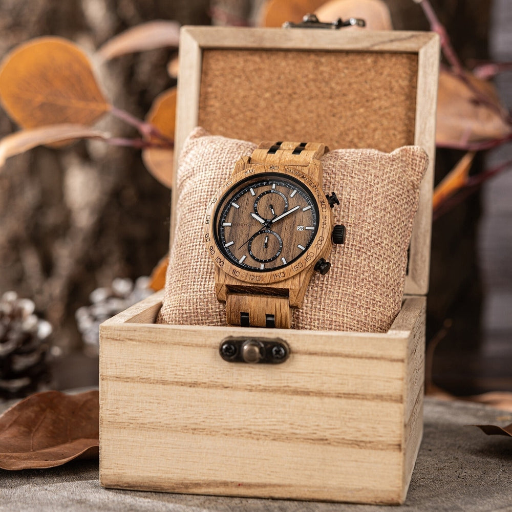 Mokozai wooden wristwatch with a brown wood grain finish, black subdials, and white markers, elegantly displayed on a beige cushion inside a rustic wooden box, surrounded by autumn leaves.
